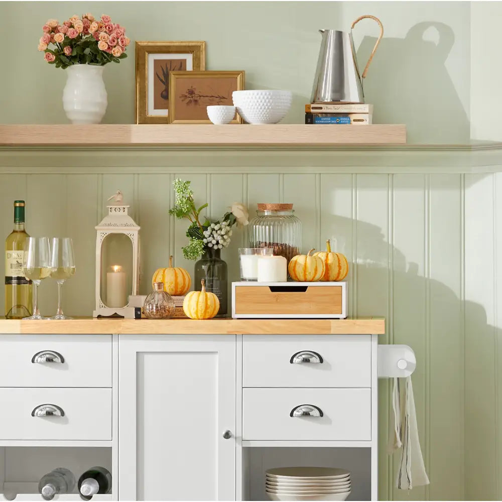 Sobuy kjøkkenøy med hvit base, trefarget topp, åpne hyller og dekorert med gresskar og tente lys.