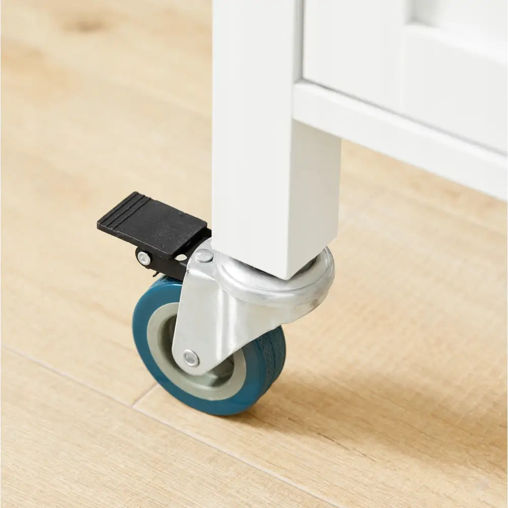 Kjøkkenøy skap, detaljert nærbilde av hvitt bein med blått hjul og svart brems mot lyse tregulv.