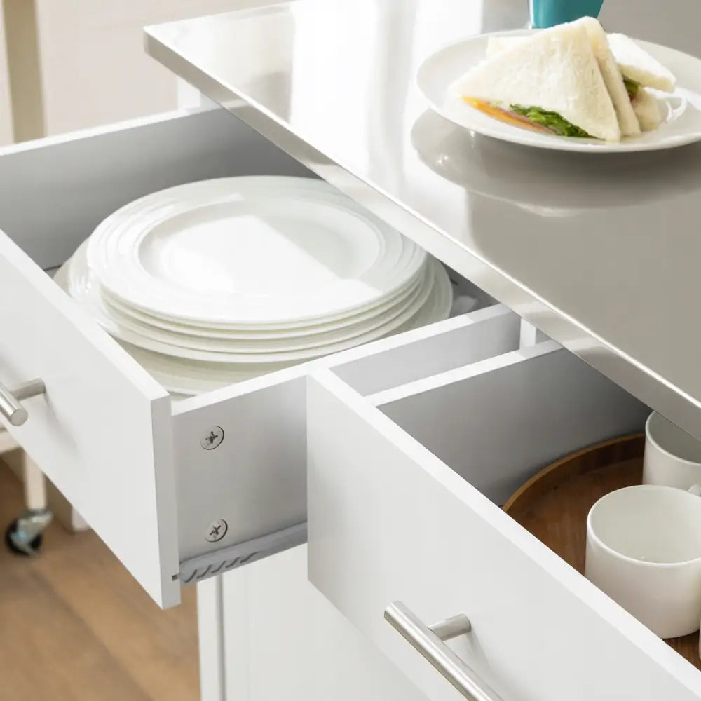 Sobuy kjøkkenøy med hvite skuffer, stablede tallerkener og kopper på trefat, sett fra skrå vinkel.