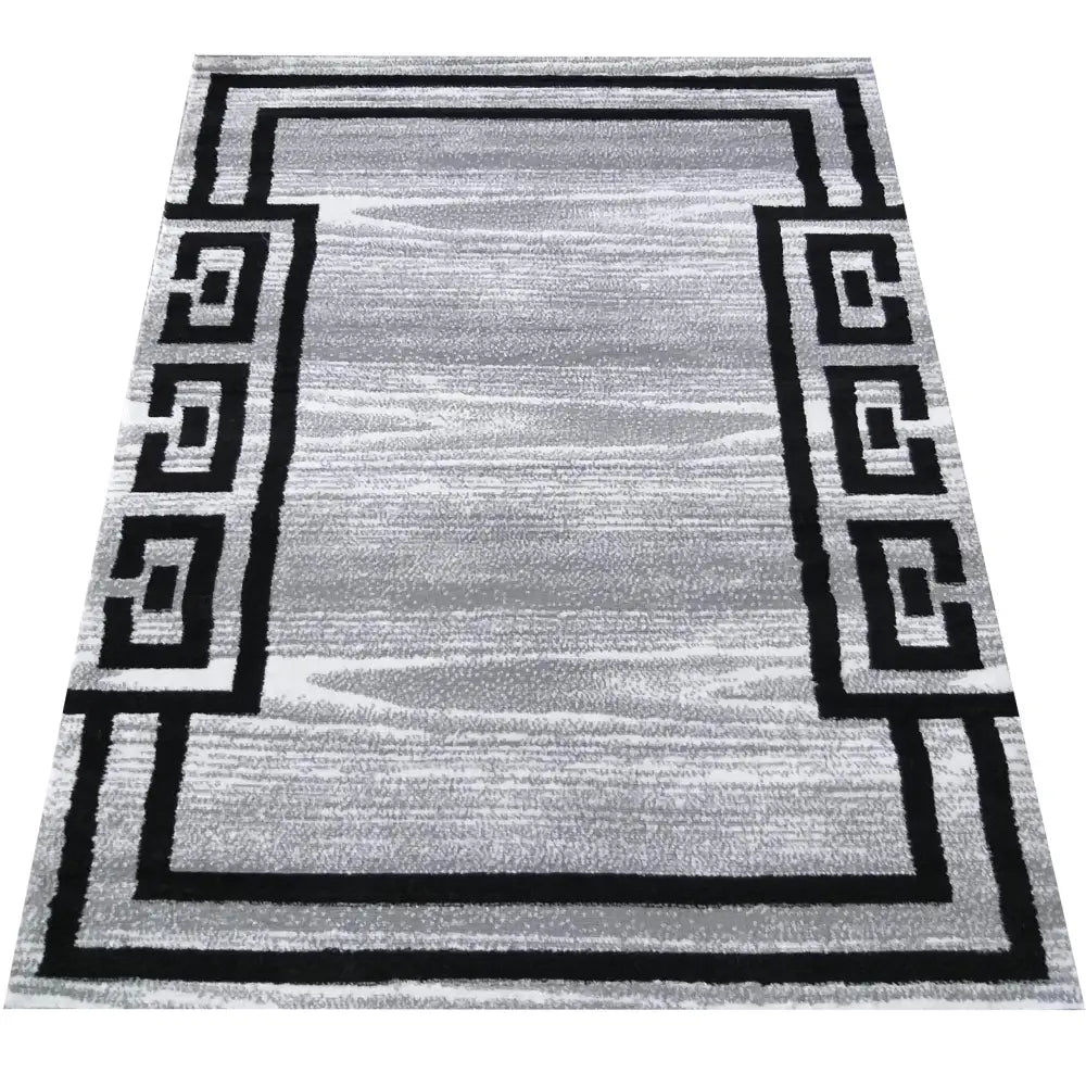 Soho Tepe grått teppe 160 x 220 cm, sett ovenfra med sort, geometrisk kant og melert grå overflate.