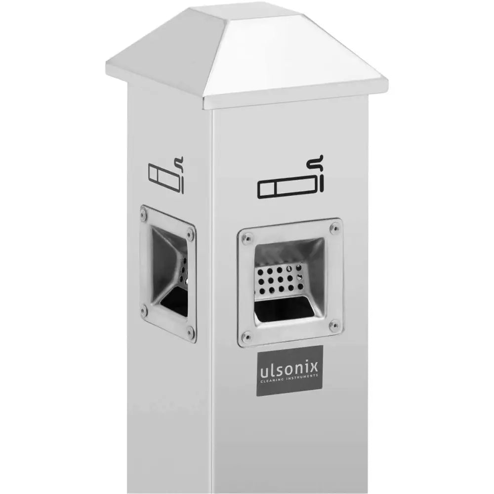 Sølv stående lukket askebeger, skråvisning med to askebegeråpninger og tydelige røykesymboler på sidene.