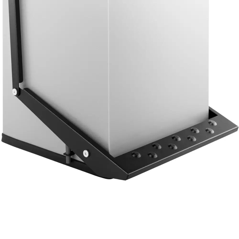 Søppelbøtte i stål, nærbilde av sort fotplate med knotter og grå ramme sett fra hjørne i skrå vinkel.