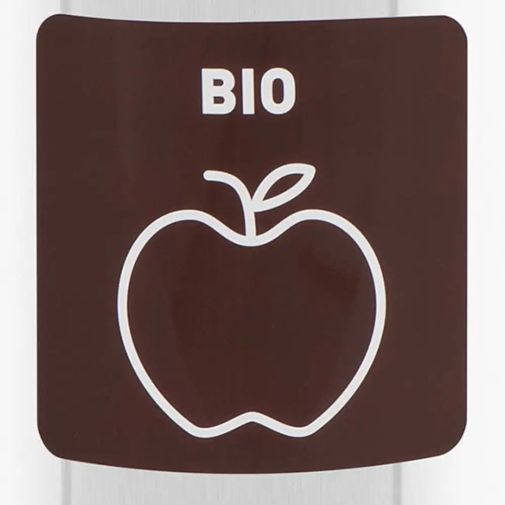 Brun bioetikett med hvit epleillustrasjon på sølvfarget søppelbøtte, nærbilde av produktdetalj.