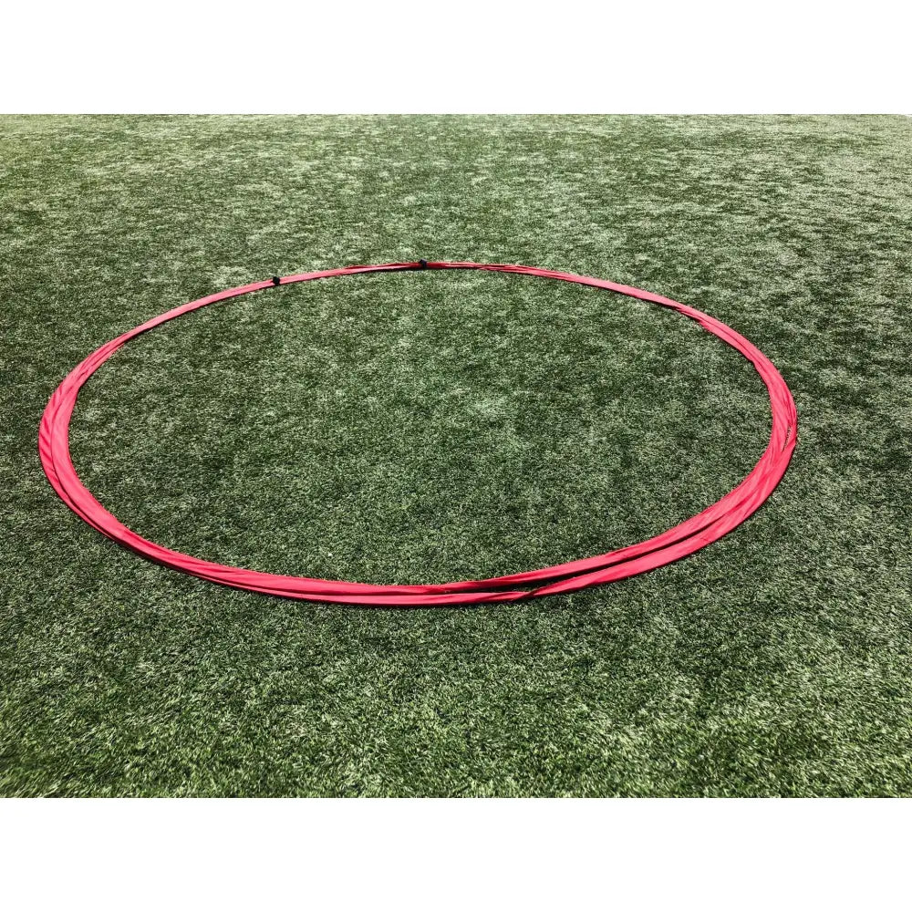 Spillet hjul Tiki Taka, rød rund bøyle fotografert skrått ovenfra på grønt kunstgress uten forstyrrelser.