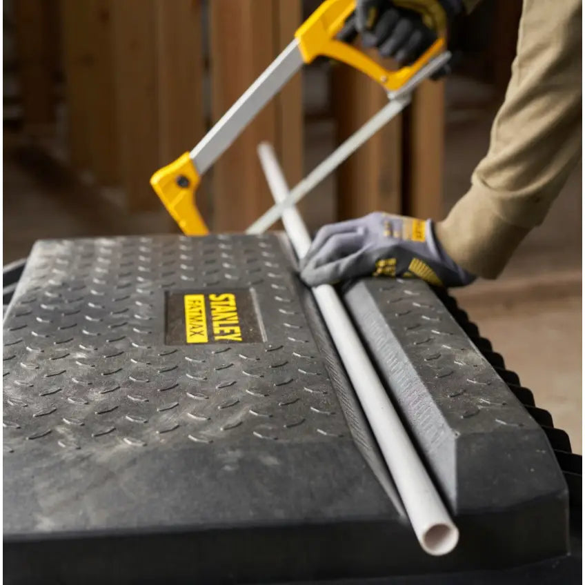 Stanley verktøykasse på hjul 113L brukes som arbeidsbenk mens en person sager rør med baufil.