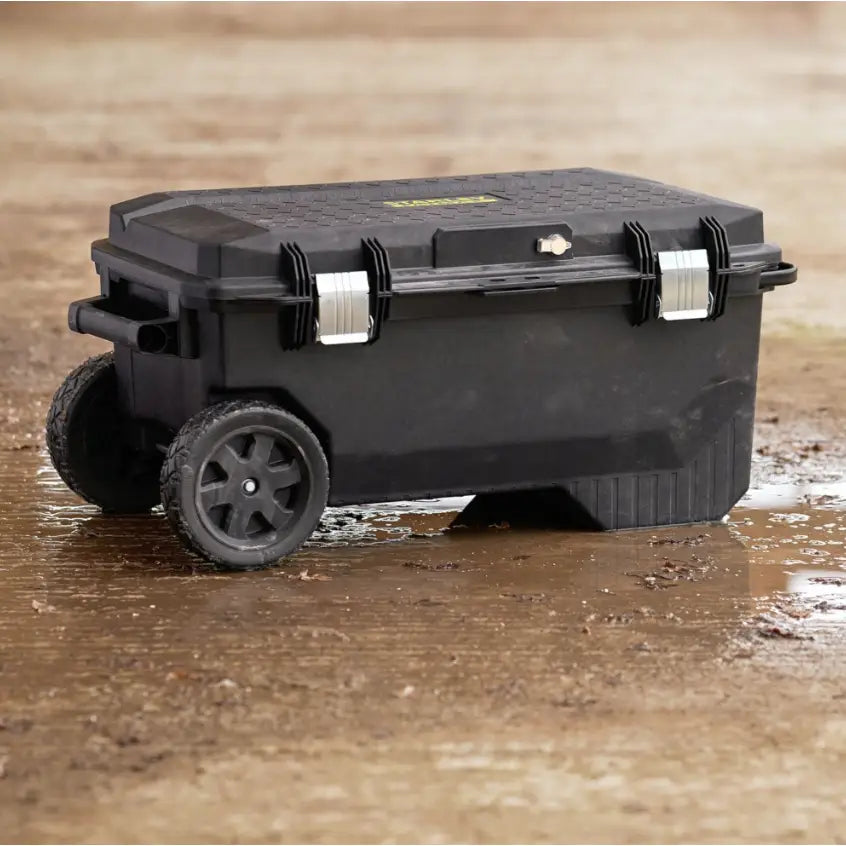 Stanley verktøykasse på hjul 113L, sidevisning med store hjul og metallspenner på våt bakke utendørs.