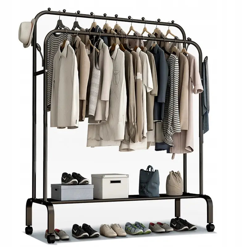 Stativ kleshenger i svart metall, dobbel hengestang med lyse klær, sko og vesker plassert på skohylle med hjul.