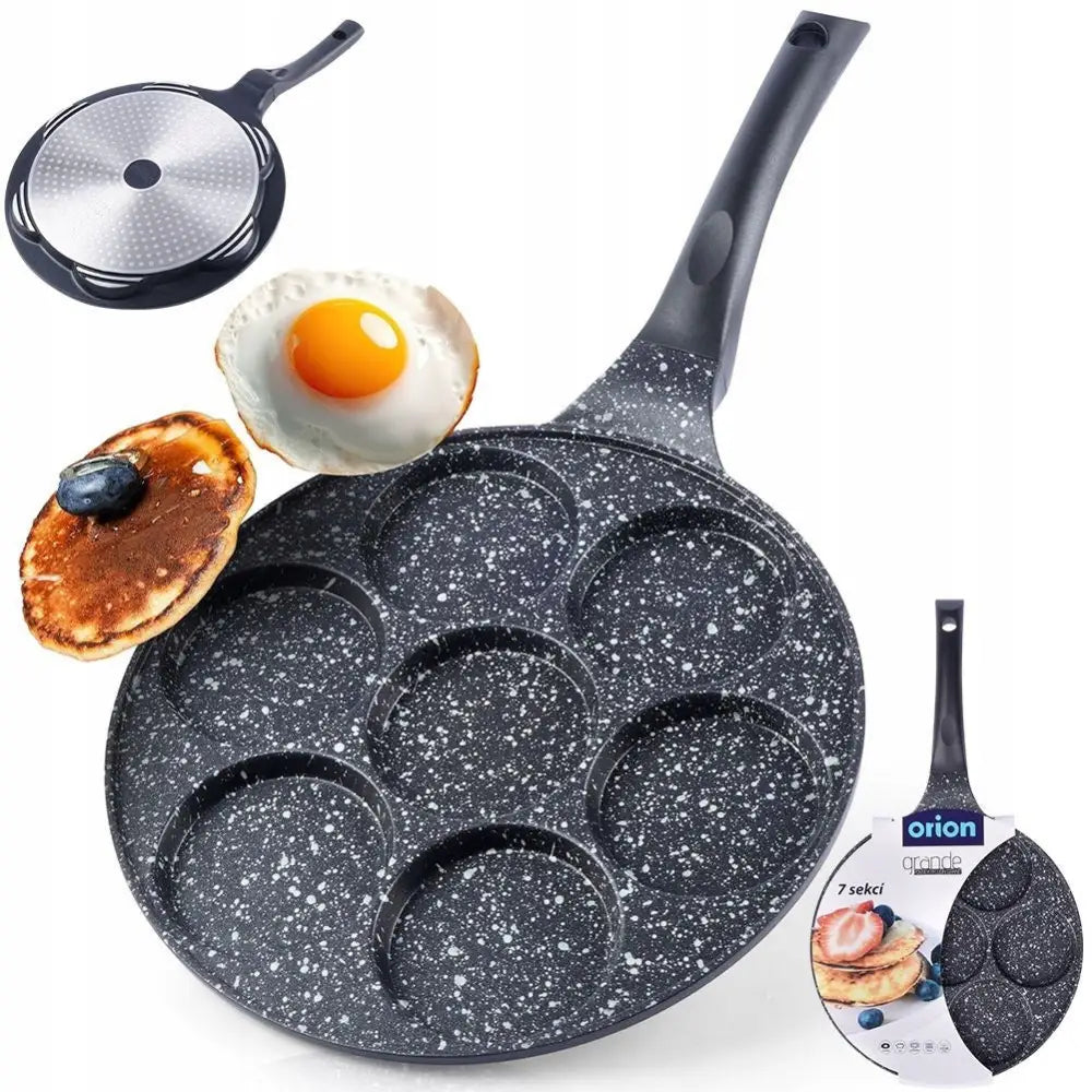Stekepanne i granitt med syv runde former, sett skrått ovenfra, sammen med ferdigstekt egg og pannekake.