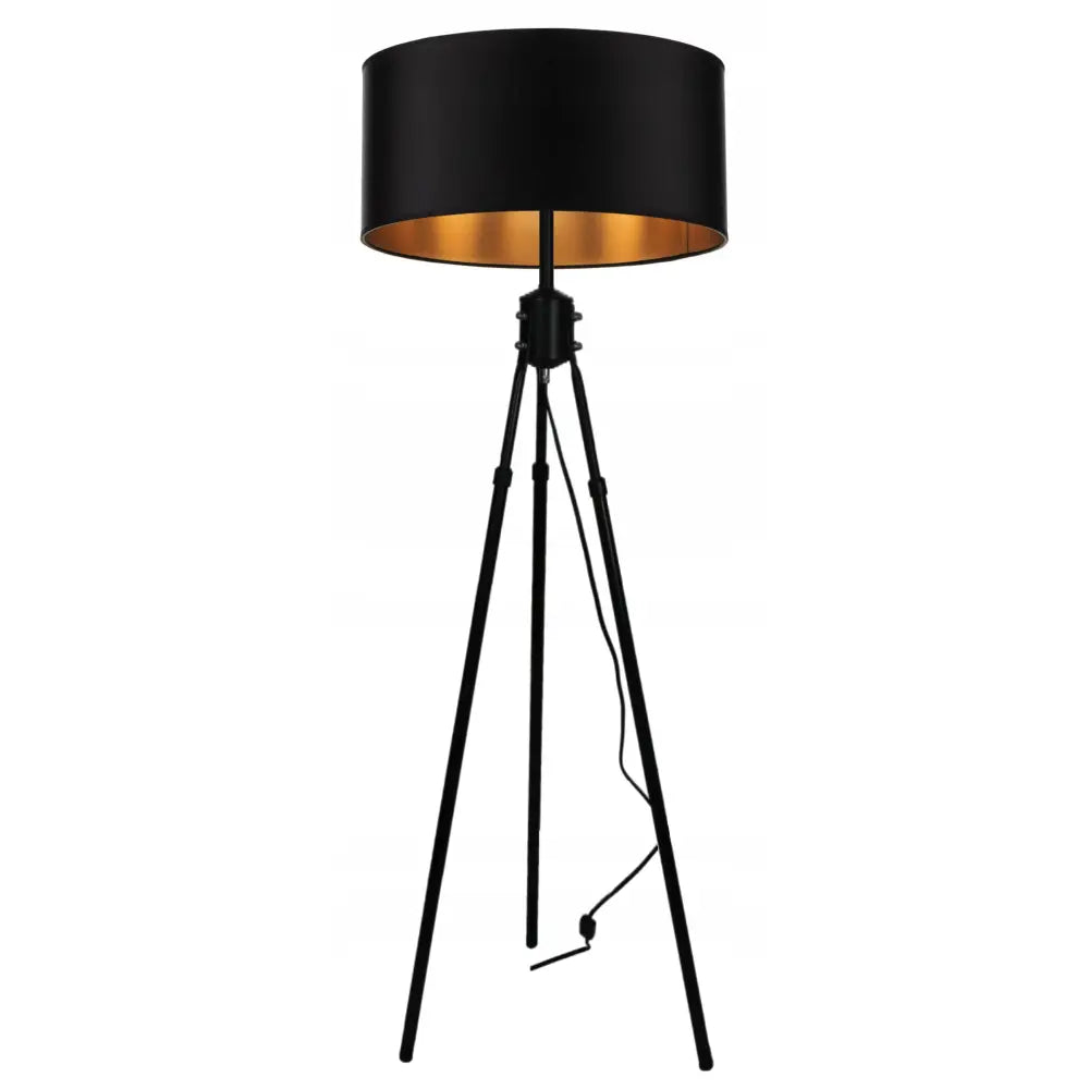 Stemningsfull gulvlampe med sorte trebein, rund skjerm med gyllen innside og synlig strømkabel.