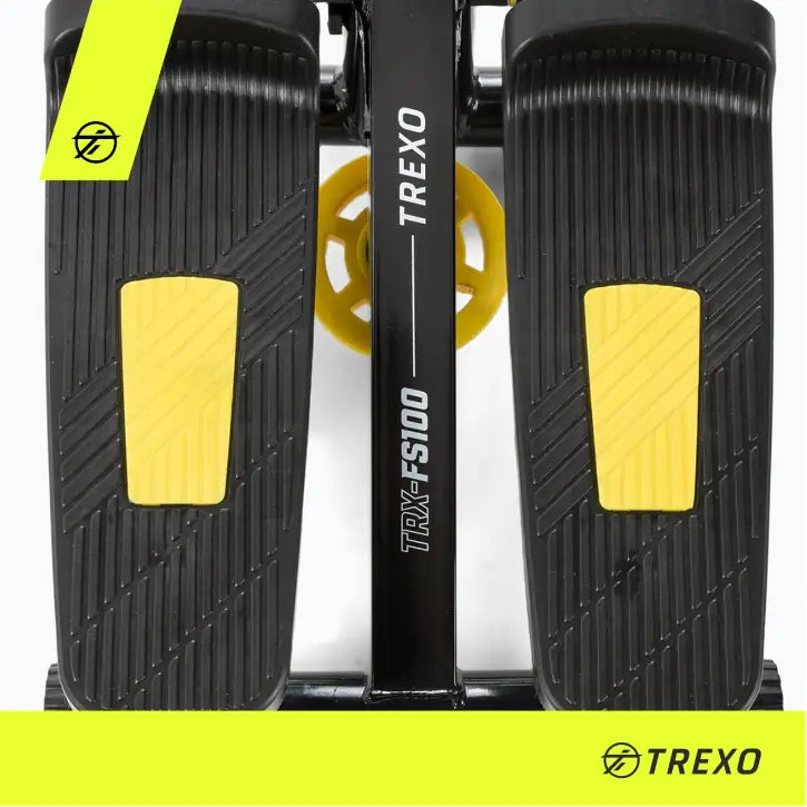 Stepper for aerobic, oversiktsbilde av sorte pedaler med gul struktur og sentrerte gule hjul på metallramme.