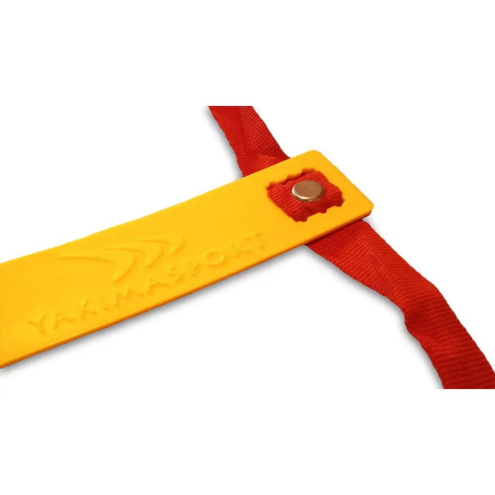 Stige for koordinering, nærbilde av gul plastbrikke med logo på rødt bånd festet med metallnagle.