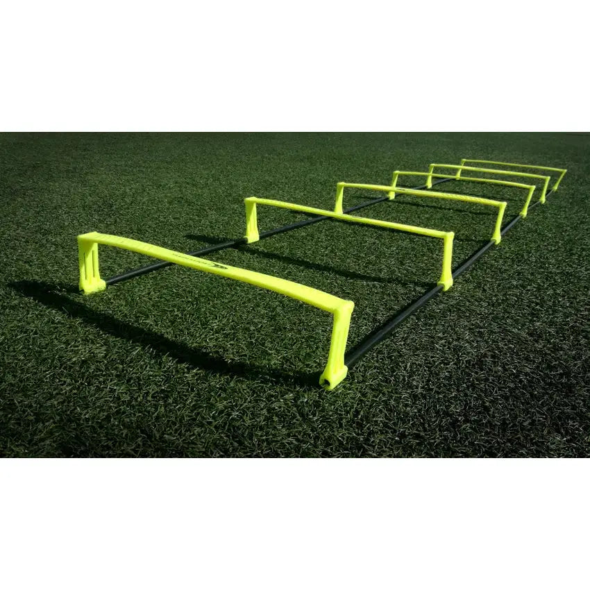 Koordineringsstige med fem neon-gule hinder og svarte stenger, sett skrått på kunstgress.