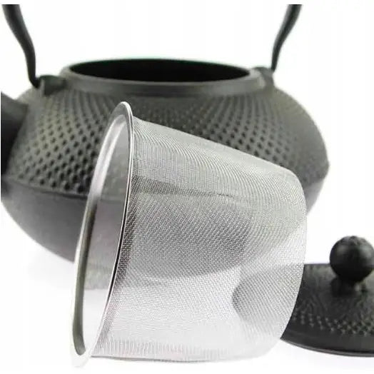 Støpejern tekanne med strukturert overflate, vist sammen med infuser og lokk i skråperspektiv.