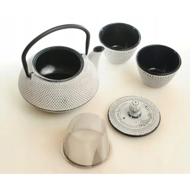 Støpejernskanne med sort håndtak og to hvite kopper, skrå vinkel som viser avtakbart lokk og metall-sil.