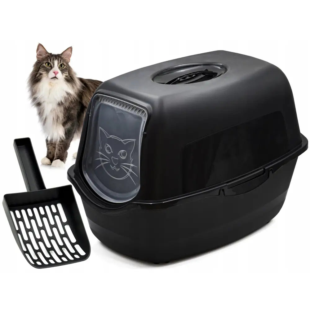 Stor kattetoalett i svart plast med gjennomsiktig dør med katteansikt, inkludert sort spade og katt i bakgrunnen.
