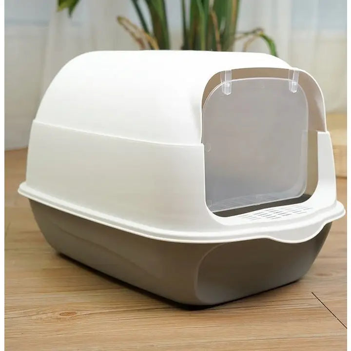 Stor lukket kattetoalett med hvitt lokk, grå bunn og gjennomsiktig svingdør, plassert på lyst tregulv.