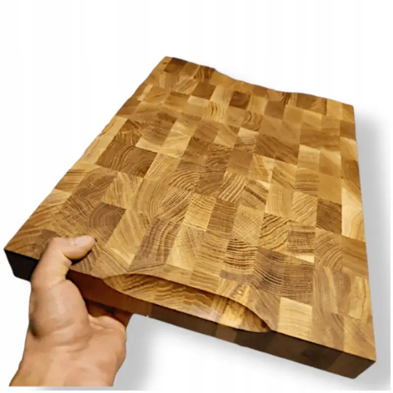 Stor skjærebrett i lyst tre med kubbemønster, vist fra hjørnet med håndgrep og synlig gripehull.