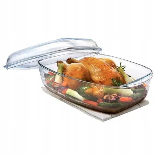 Stort ildfast fat i klart glass med lokk, fylt med stekt kylling og grønnsaker, sett fra skrå vinkel.