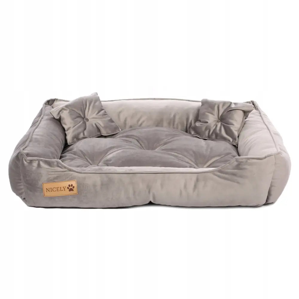 Stort velur hundeseng i lysegrått med høye kanter, to puter og brunt poteavtrykk-merke foran, frontvisning.