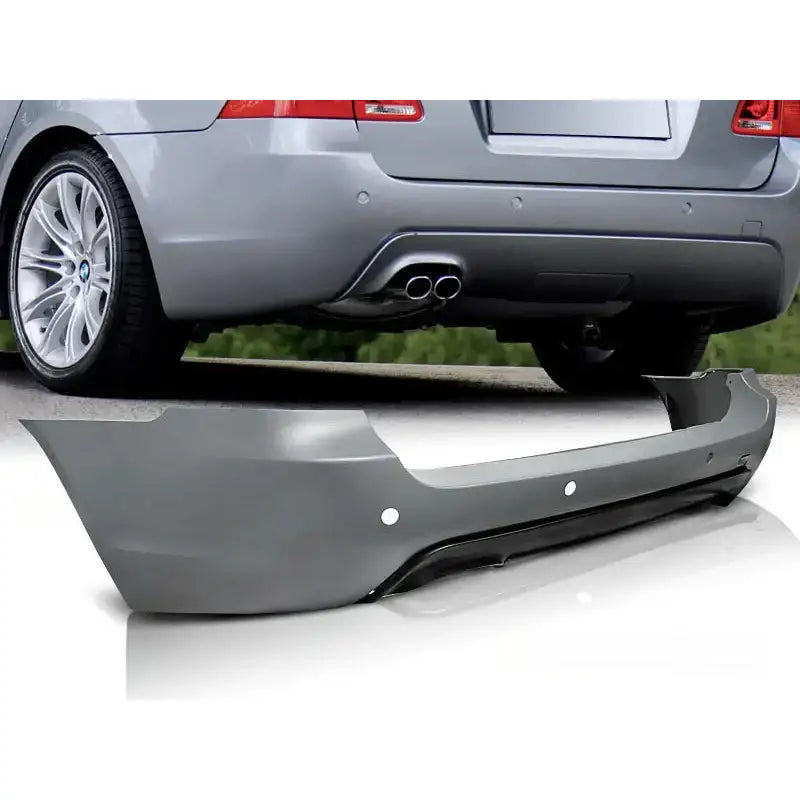 Støtfanger bak Bmw E61 03-07 Touring M-Pack PDC i grå plast sett fra skrå vinkel foran bil.