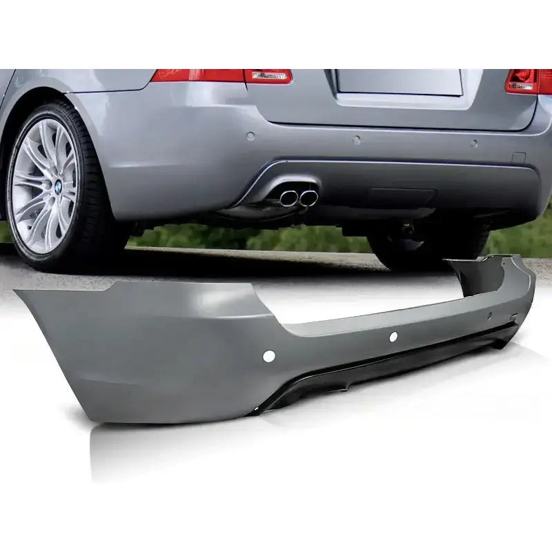 Støtfanger bak Bmw E61 08-10 Touring M-Pack PDC i grå plast med sensorhull, vist fra skrå vinkel.