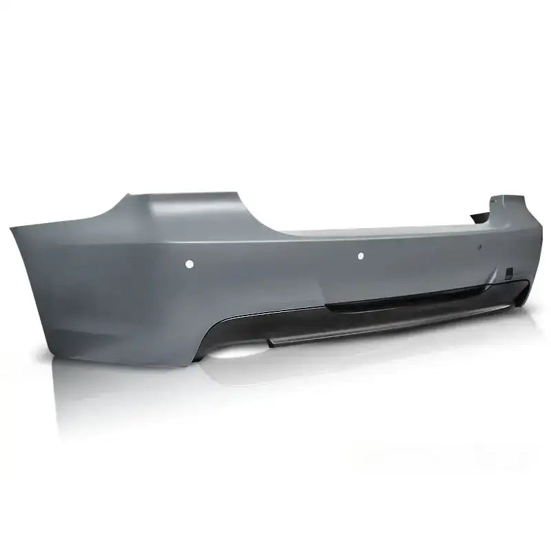 Bakfanger Bmw E90 09-11 M-Pack PDC i grå plast med sensorhull og svart nedre del, skrå bakfra.