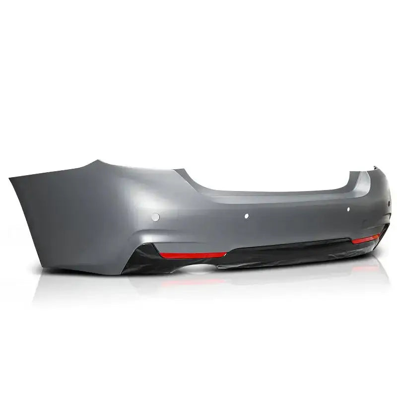 Bakfanger BMW F32/F33 M-Tech style i grå plast med PDC-sensorer og røde reflekser, sett skrått bakfra.