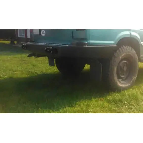 Bakfanger Land Rover Discovery I Lang med sorte terrengdekk og grønne karosseridetaljer utendørs.