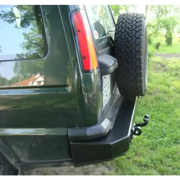 Bakfanger Land Rover Discovery II i sort metall med tilhengerfeste og reservehjul, sett skrått bakfra.