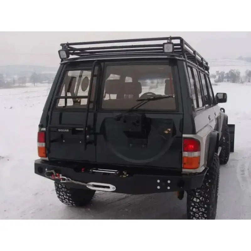 Bakre støtfanger med vinsj plate på Nissan Patrol Y60 sett bakfra med stige og takstativ på snø.