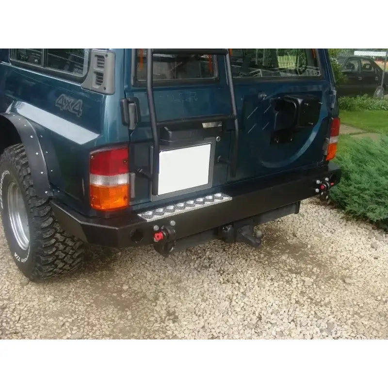 Bakre støtfanger Nissan Patrol Y60 i svart metall med stigtrinn og runde tauekroker, nærbilde utendørs.