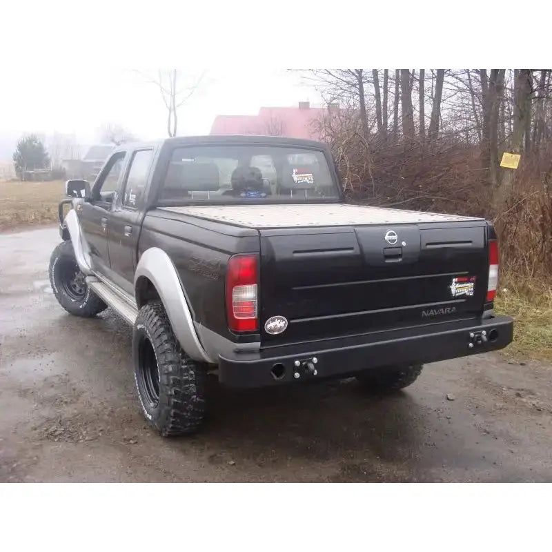 Bakfanger på Nissan Pickup D22 01-04 med sorte terrengdekk og lukkede lasteplan, sett bakfra.