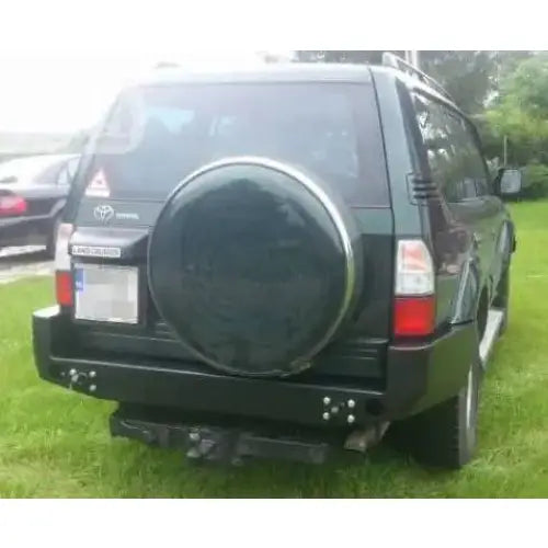 Bakfanger til Toyota Land Cruiser J9 i stål, sett bakfra med reservehjul og mørk bil på gress.
