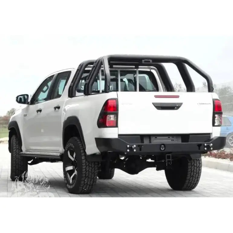Støtfanger bak på hvit Toyota Hilux Revo 16- med svart veltebøyle og terrengdekk, skrå bakfra.