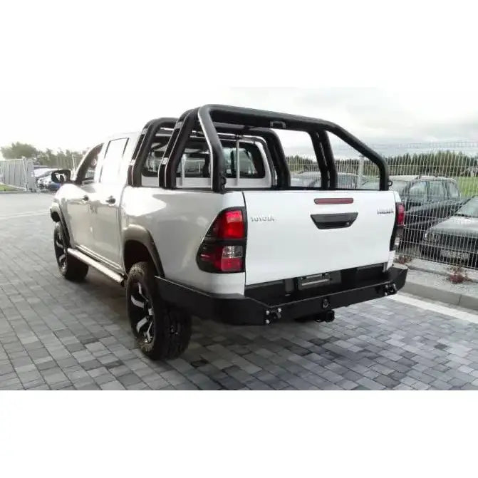 Støtfanger bak på Toyota Hilux Revo 16- lang, hvit pickup med sorte stigbøyler, sett bakfra utendørs.