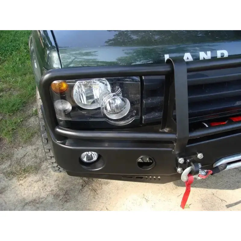 Front bumper på Land Rover Discovery II med sort bullbar, hovedlykt, tåkelys og vinsj med rød stropp.
