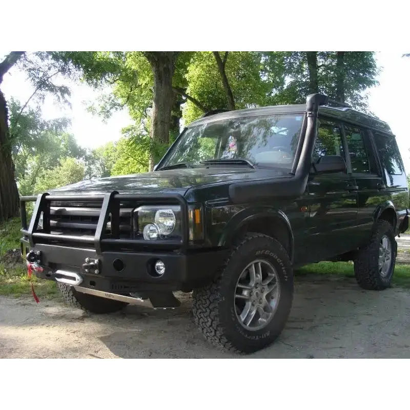 Frontbumper med bullbar på mørkegrønn Land Rover Discovery II med vinsj og snorkel i skogsområde.