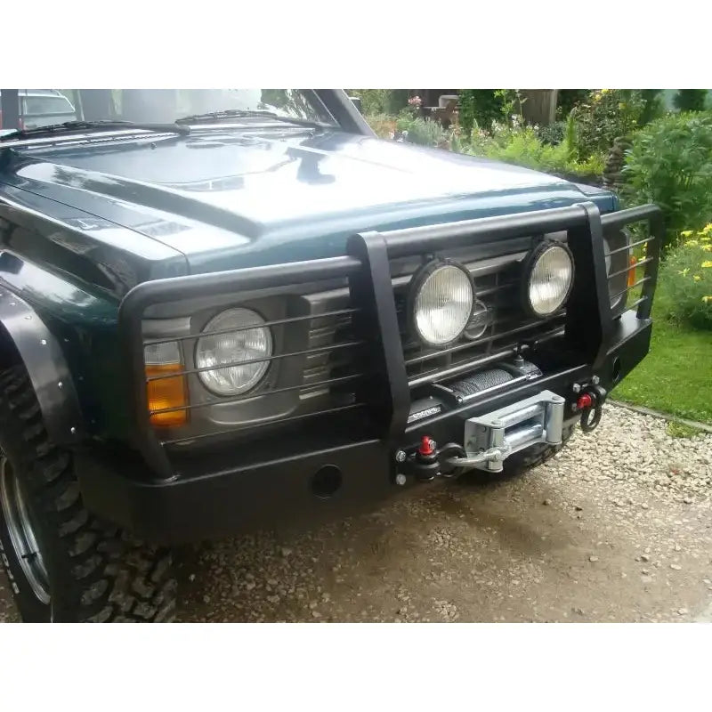 Frontfanger til Nissan Patrol Y60 med integrert bullbar, ekstra lykter og vinsj sett skrått forfra.