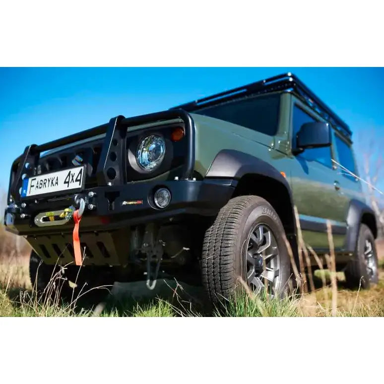 Frontfanger på Suzuki Jimny IV 1.5 med bullbar, vinsj og offroad-dekk i grønt utendørsmiljø.