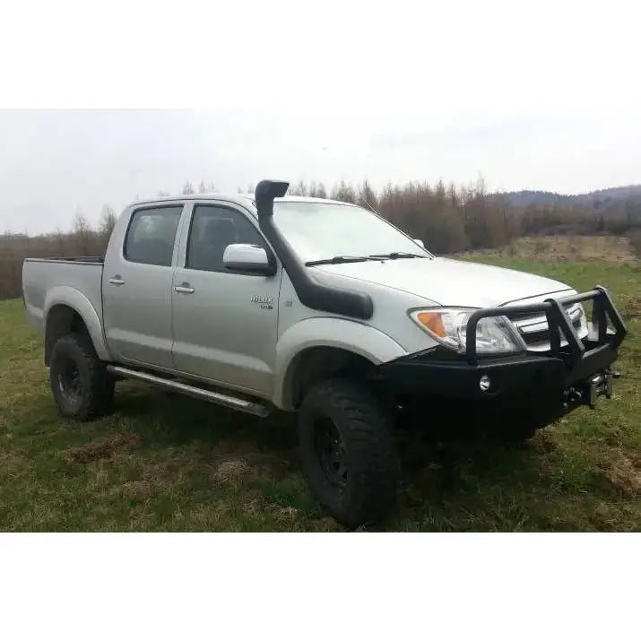 Front bumper på Toyota Hilux 05-11 med svart bullbar, snorkel og terrengdekk, sett skrått forfra utendørs.
