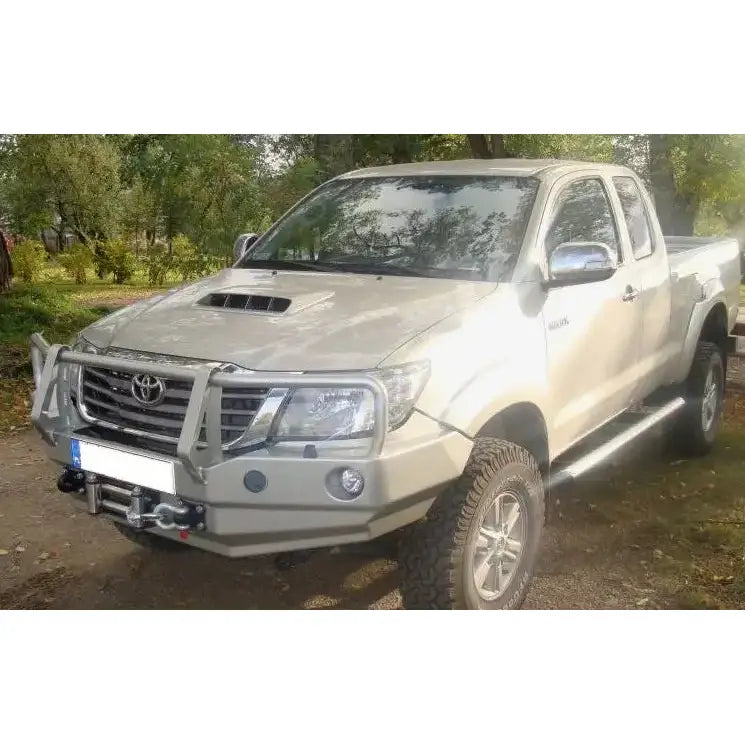 Frontfanger på beige Toyota Hilux 11-15 med bullbar, terrengdekk og vinsj sett skrått forfra.