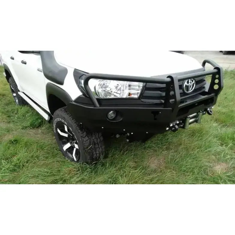 Frontbumper til Toyota Hilux Revo med bullbar, montert på hvit pickup med terrenghjul på gress.