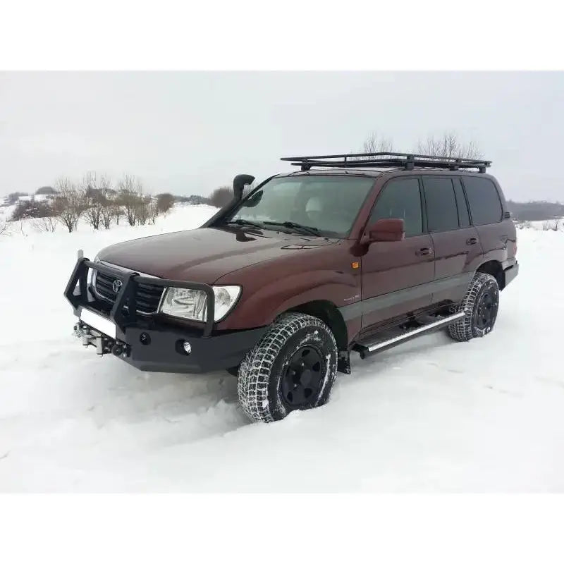 Støtfanger foran med bullbar på mørkerød Toyota Land Cruiser J100 med takstativ og vinterdekk på snø.