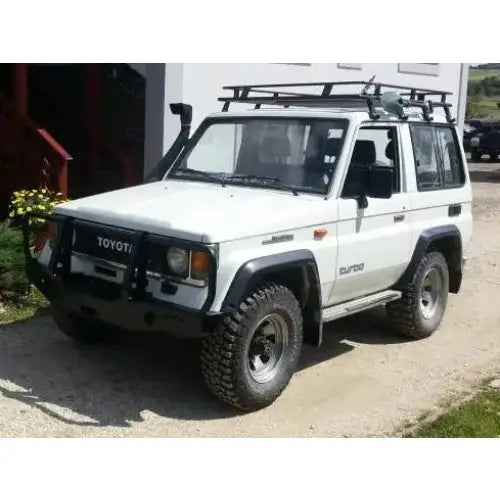 Front bumper på Toyota Land Cruiser J70 med bullbar, store terrengdekk og takstativ, sett skrått forfra.