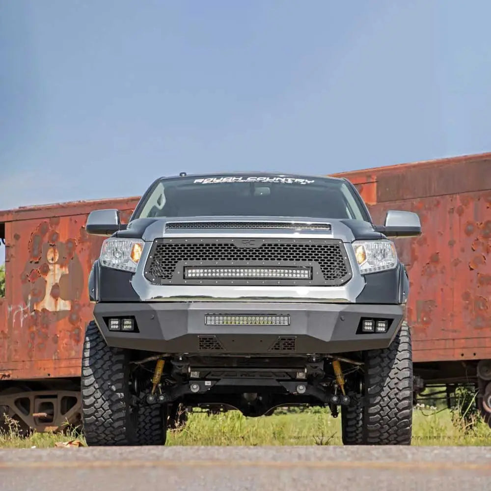 Støtfanger foran med LED-lys Rough Country montert på svart Toyota Tundra foran rusten togvogn.