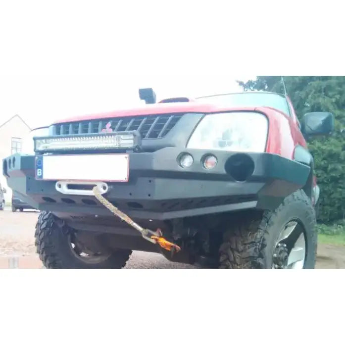 Front bumper på Mitsubishi L200 III 96-05 med sort metallstøtfanger, tau og LED-lysramp montert foran.
