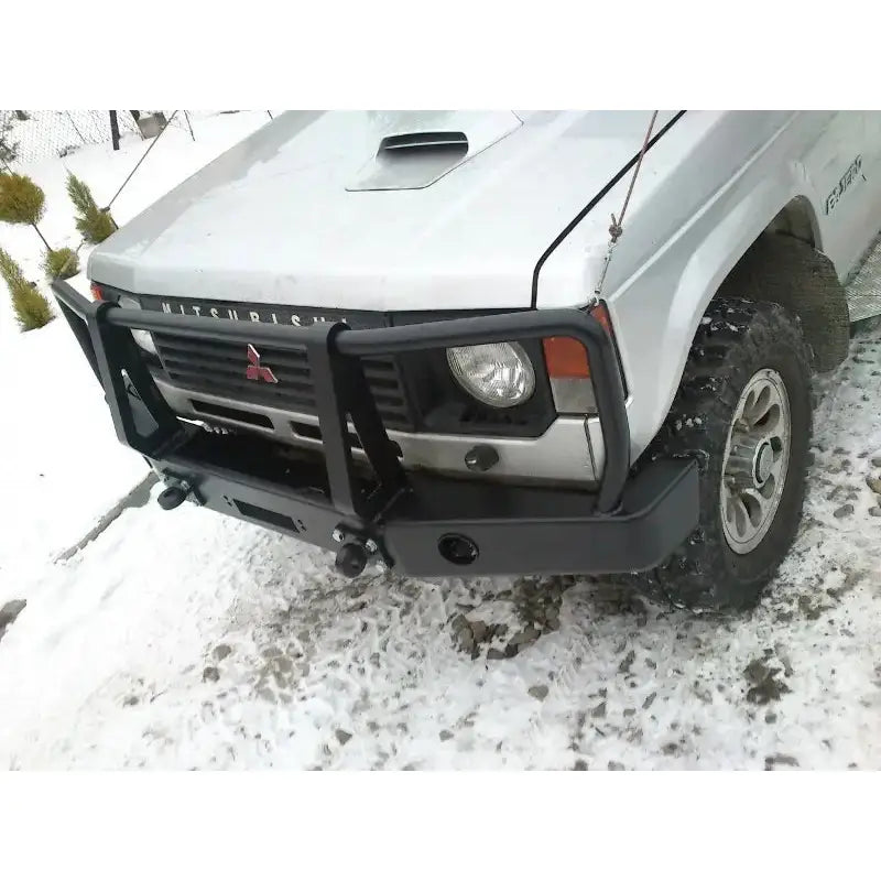 Støtfanger foran Mitsubishi Pajero I med bullbar montert på sølvfarget bil, sett skrått forfra på snø.