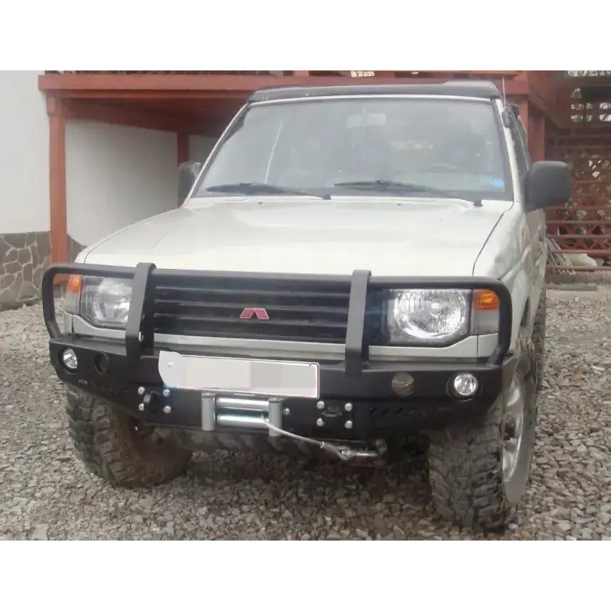 Frontfanger Mitsubishi Pajero II med sort bullbar og vinsj, store terrengdekk, grusunderlag.