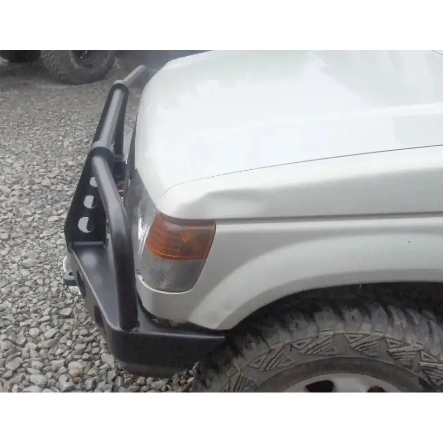 Front bumper til Mitsubishi Pajero II med bullbar, montert på hvit bil, sett fra siden utendørs.