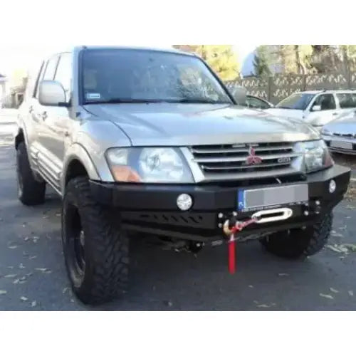 Frontbumper på Mitsubishi Pajero III med sort stålfanger, vinsj og store terrengdekk, sett skrått forfra.
